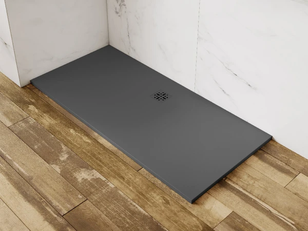Rectangular dark-grey shower tray with a square drain, white marble walls, and a wooden deck; a marble ledge holds plants and toiletries.