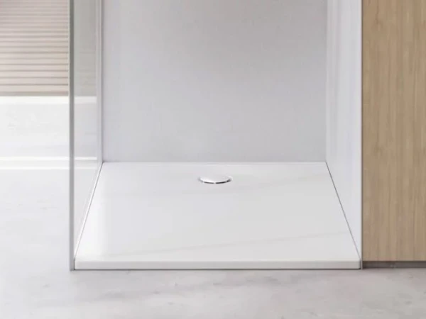 Modern shower alcove with a white rectangular tray, circular drain in the centre, clear glass panel on the left and light wood cabinetry on the right.