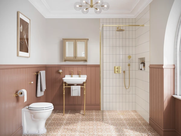 Elegant bathroom with pink wainscoting, white sink on a gold pedestal stand, gold taps, glass-walled shower with gold fittings, geometric tiled floor and wall art.