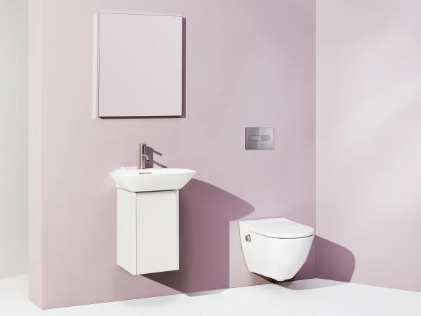 Minimalist pale-pink bathroom with a white wall-mounted sink and cabinet, a square mirror cabinet, and a wall-mounted toilet with a silver flush plate.