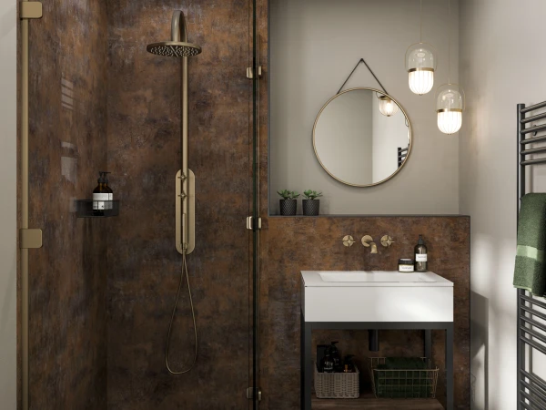 Modern bathroom with a glass shower enclosure, rust-toned tiled walls, brass fixtures, a white sink on a wood-and-metal vanity, a round wall mirror, and warm pendant lights.