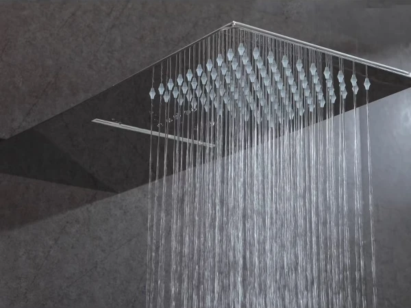 Square ceiling rainfall shower head with numerous water streams cascading down against a dark tiled wall.