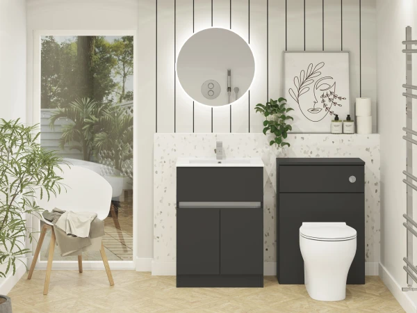 Modern bathroom with terrazzo counter and dark cabinetry, a round backlit mirror above a sink, white toilet, potted plant, abstract line art, and a glass door to a garden.