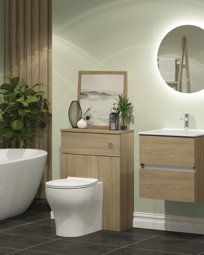 Modern bathroom with a white freestanding tub, toilet and wooden vanity with storage, a round backlit mirror, green walls, framed photos and a potted plant.