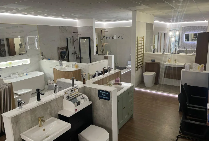 Bright bathroom showroom featuring sinks, taps, toilets, a freestanding tub, marble walls, mirrors and display cabinets.